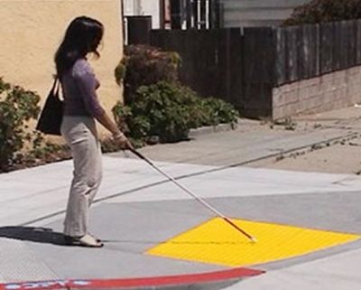 visually impaired girl using cane at a curb cut